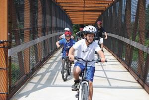 Children with the Saco Parks and Recreation summer camp ride newly donated bicycles on the John R. Andrews Eastern Trail Bridge in Saco Thursday morning.